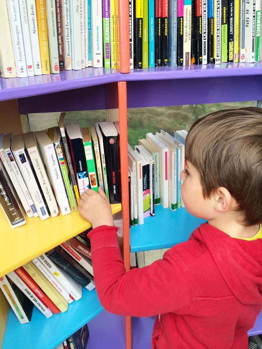 Un enfant choisi un livre dans l'ancienne cabine téléphonique